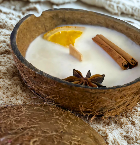 Duftkerze Coco Spice dekoriert mit Zimt, Orange und Sternanis in echter Kokosnussschale als Nahaufnahme