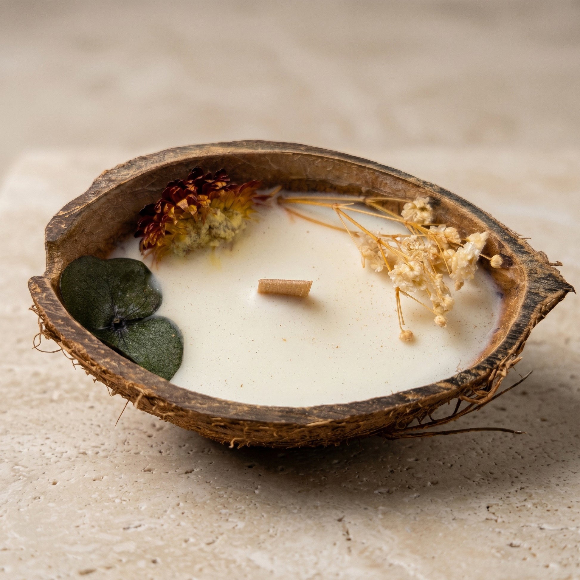 Nahaufnahme der handgefertigten Kokoskerze Coco Bloom von Kristalla in natürlicher Kokosnussschale mit Holzdocht und Sojawachs