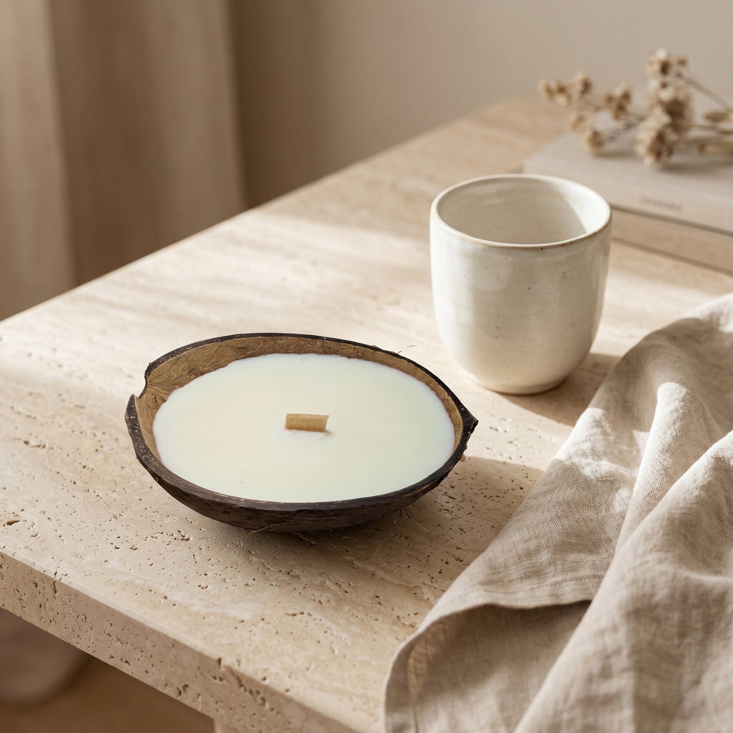 Handgefertigte Kokoskerze Coco Dream von Kristalla in natürlicher Kokosnussschale auf stilvollem Steintisch mit warmem Ambiente