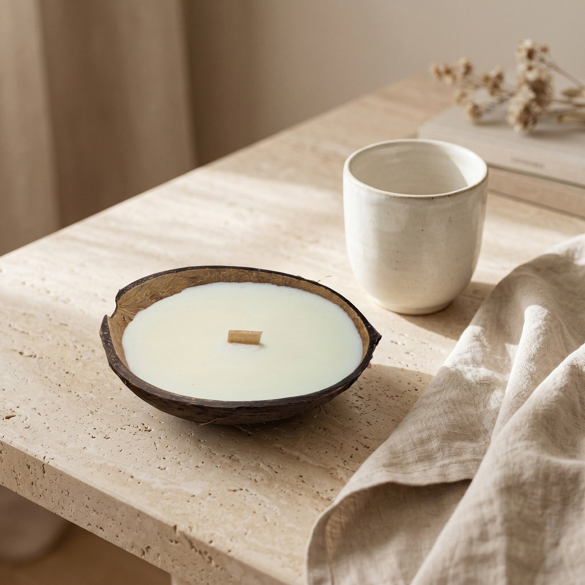 Handgefertigte Kokoskerze Coco Dream von Kristalla in natürlicher Kokosnussschale auf stilvollem Steintisch mit warmem Ambiente