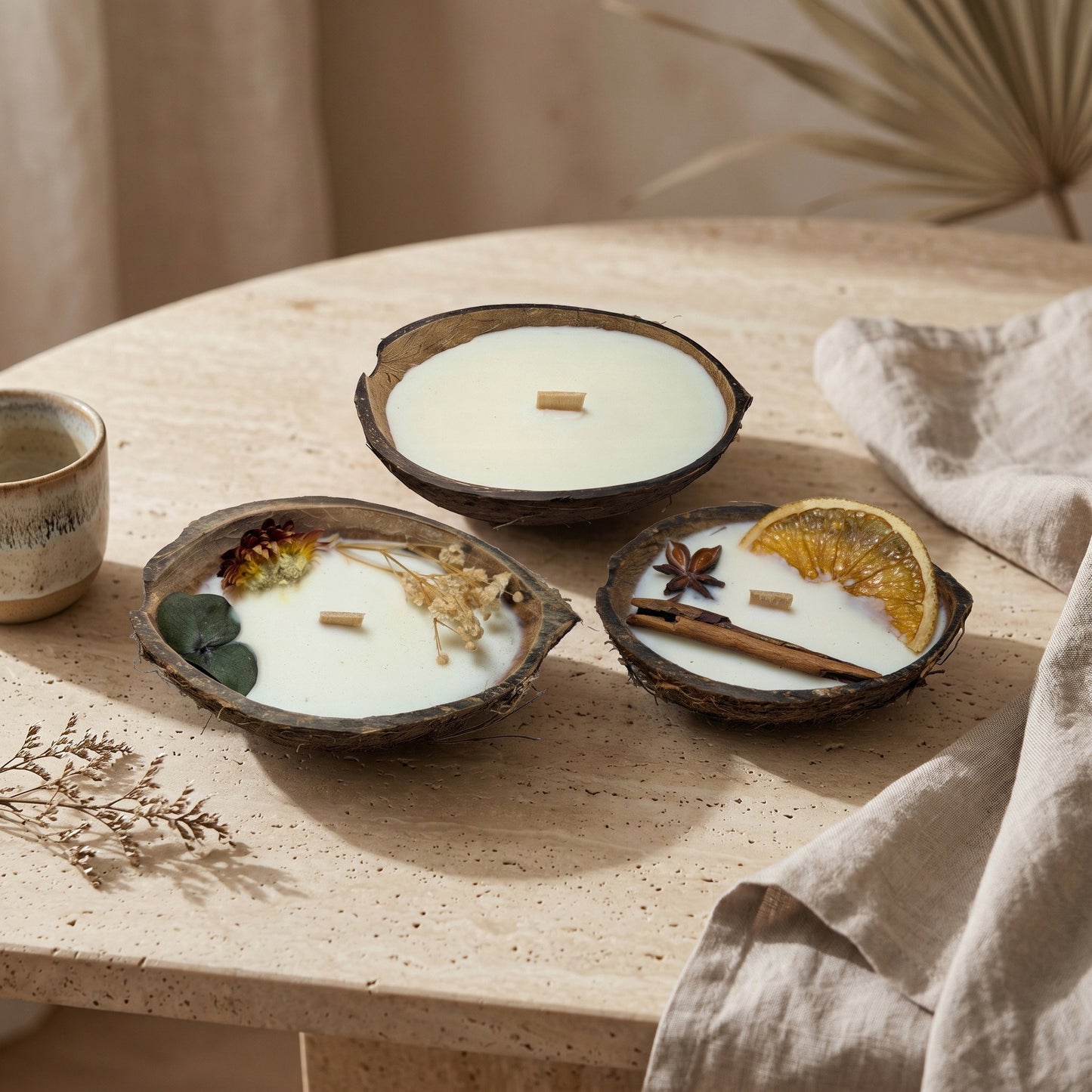 Handgefertigte Kokoskerzen Kollektion von Kristalla in natürlichen Kokosnussschalen mit Sojawachs und Holzdocht auf hellem Tisch in warmer, stilvoller Umgebung